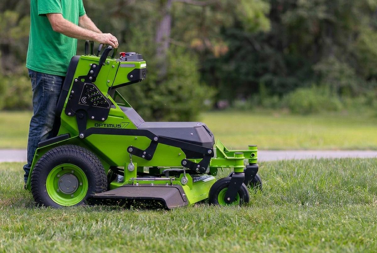 Ryan Wallace operating a solar-charged electric stand-on mower on an Oakville residential lawn